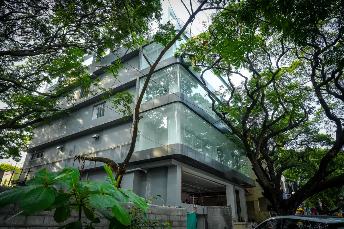 Urban Premium Coworks building with glass facade among large trees