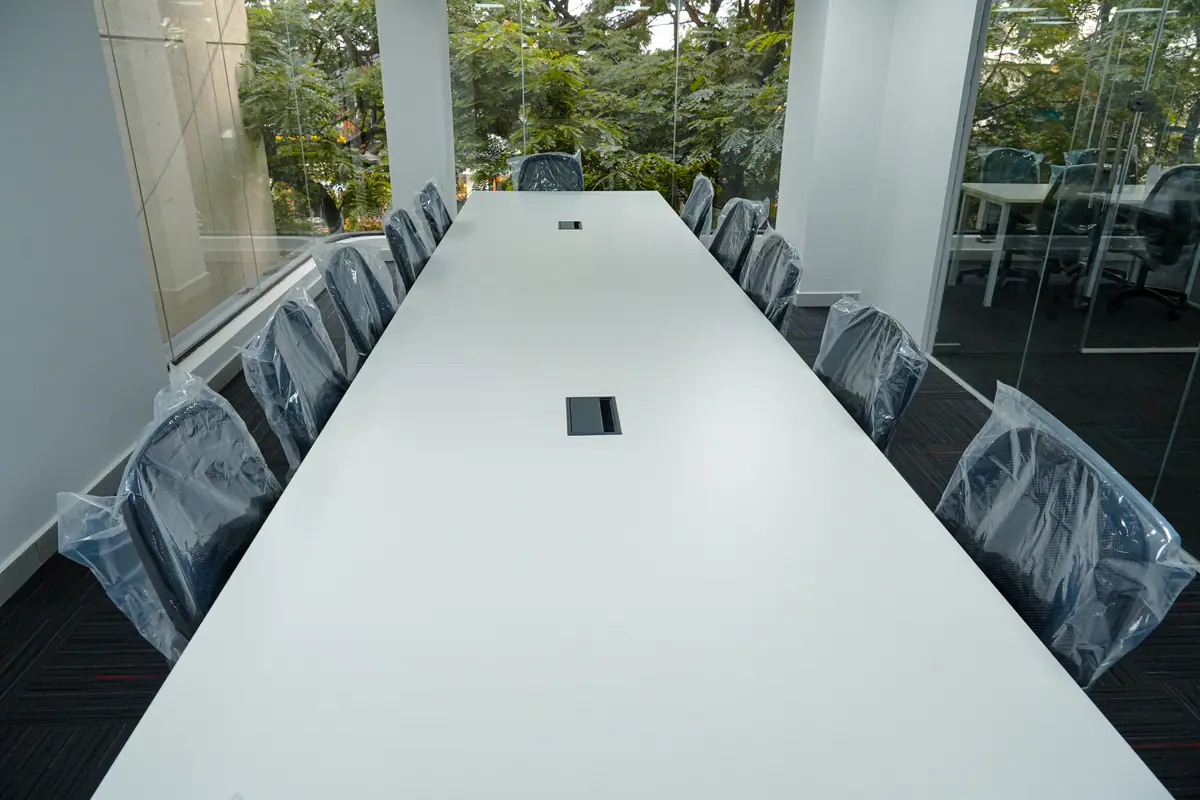 Long white meeting table with chairs along a glass wall