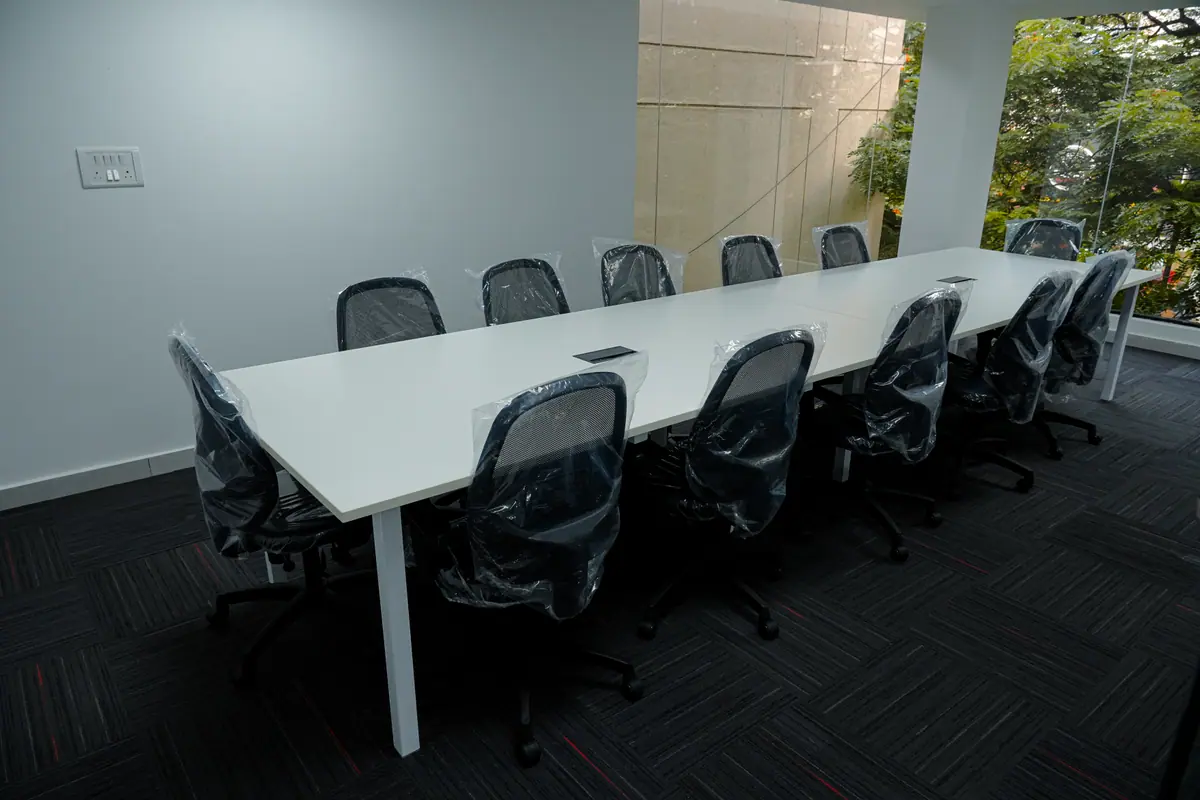 Boardroom table with black ergonomic chairs beside a window