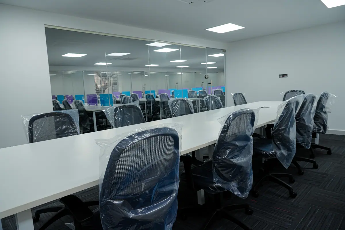 Meeting room with a long table and the workspace visible through glass