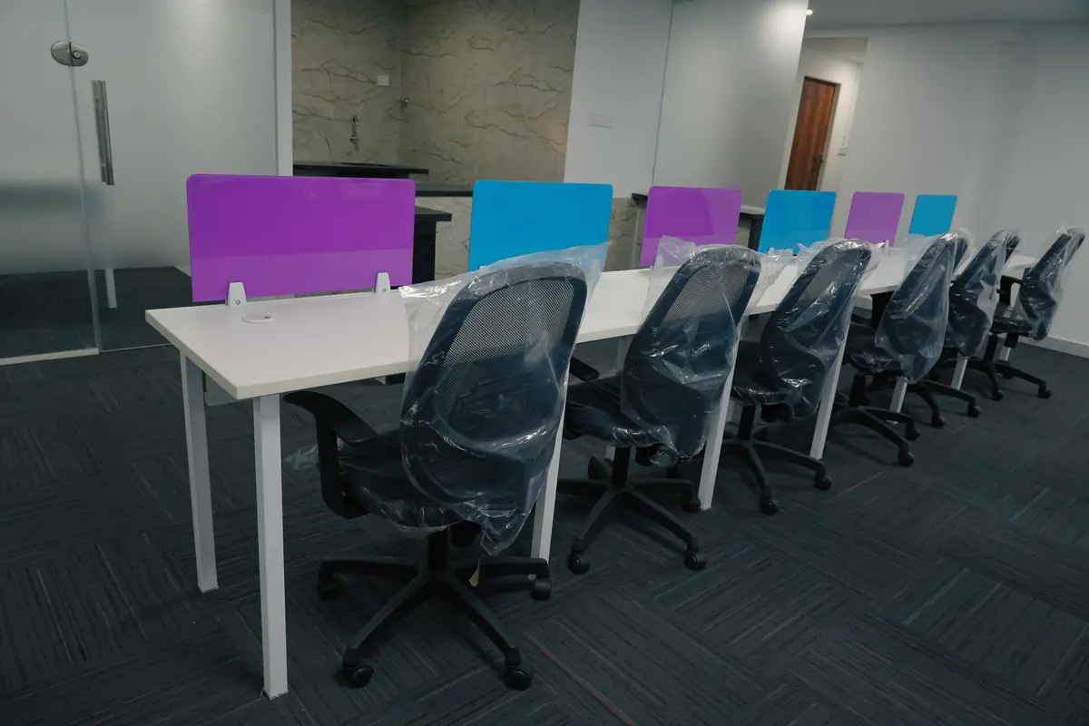 Desk with a purple partition and mesh chairs near a glass door