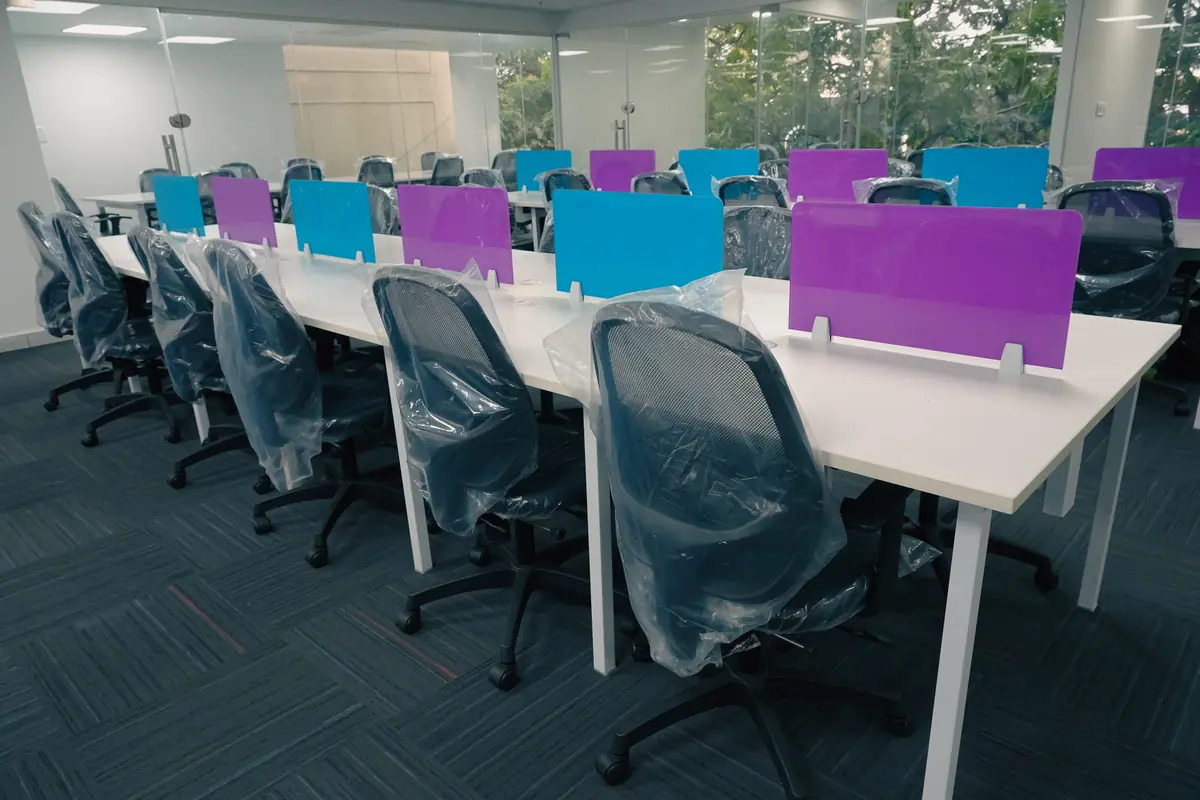 Open desks with partitions and glass-walled rooms behind