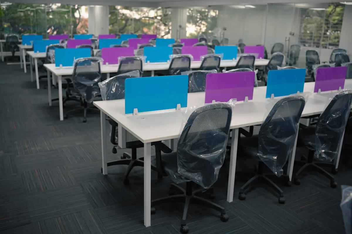 Shared desks with blue and purple partitions and ergonomic chairs
