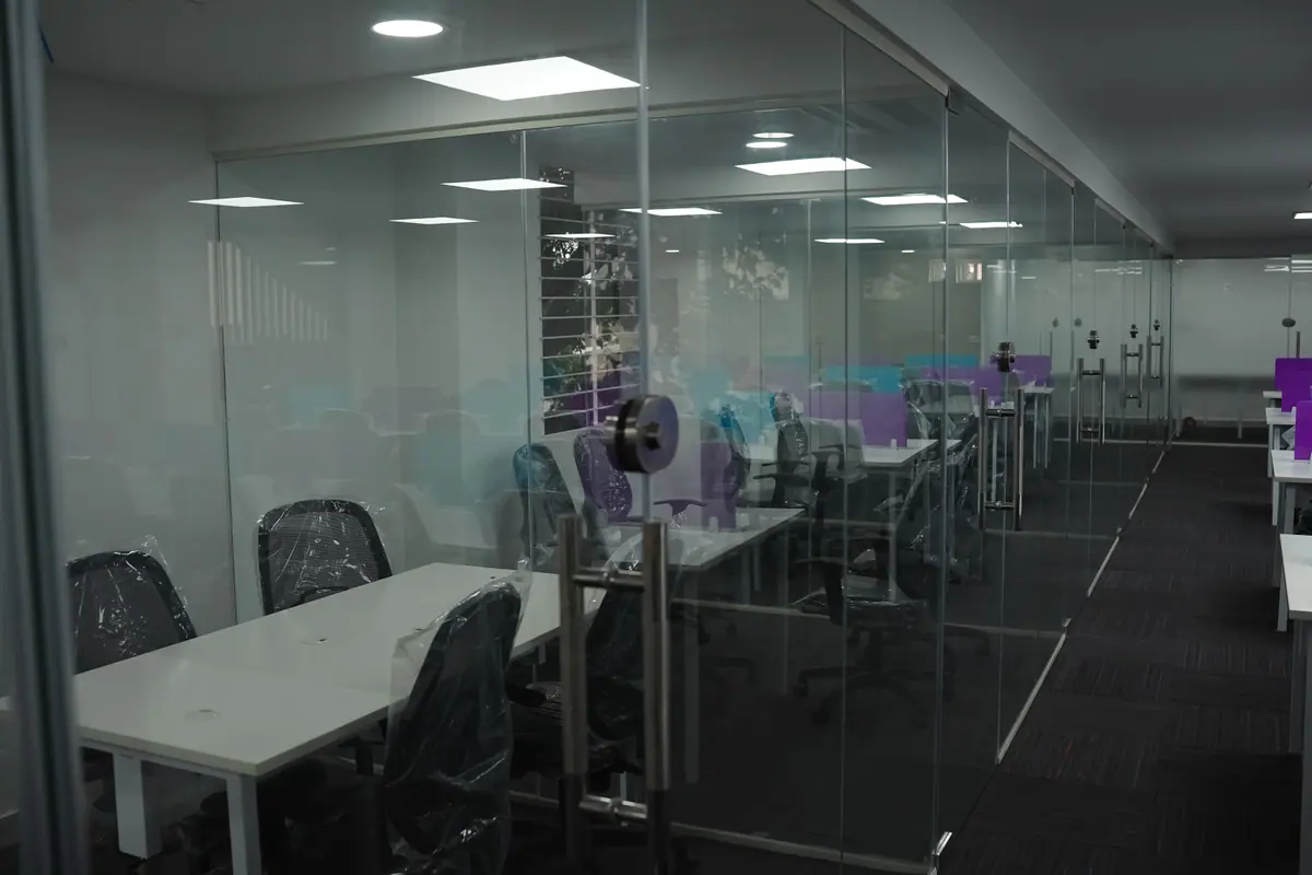 Private glass cabin with a table, with the open workspace beyond