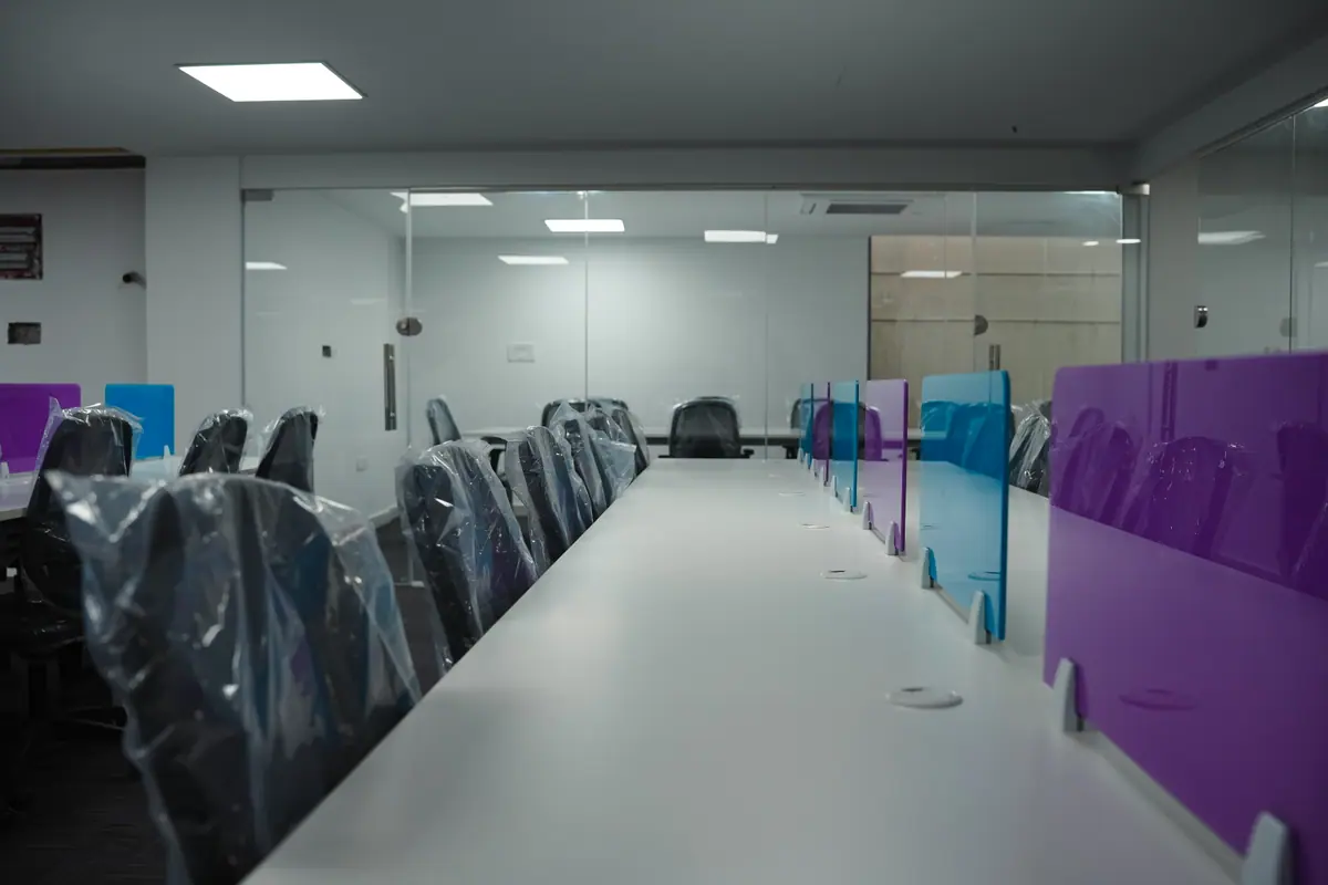 Long table with chairs and coloured screens leading to a glass-walled room
