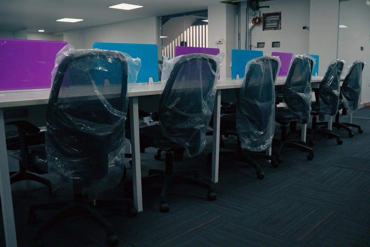 Row of ergonomic mesh chairs at a long desk with coloured partitions
